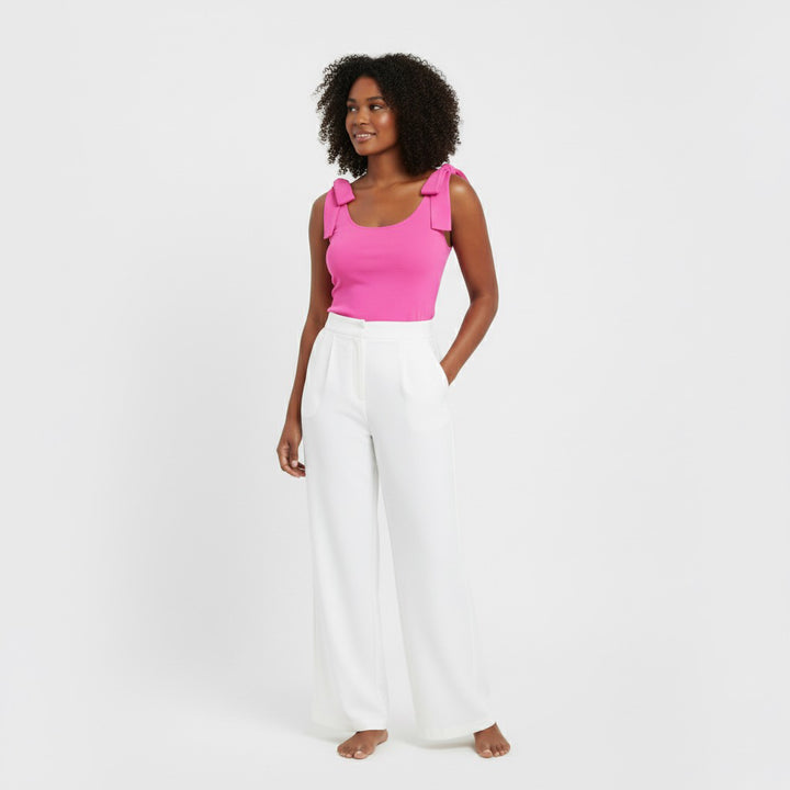 Woman wearing a Hot Pink bow-shoulder bodysuit from Motch, part of a matching mommy-and-me outfit set, styled with white wide-leg pants for a chic coordinated look.
