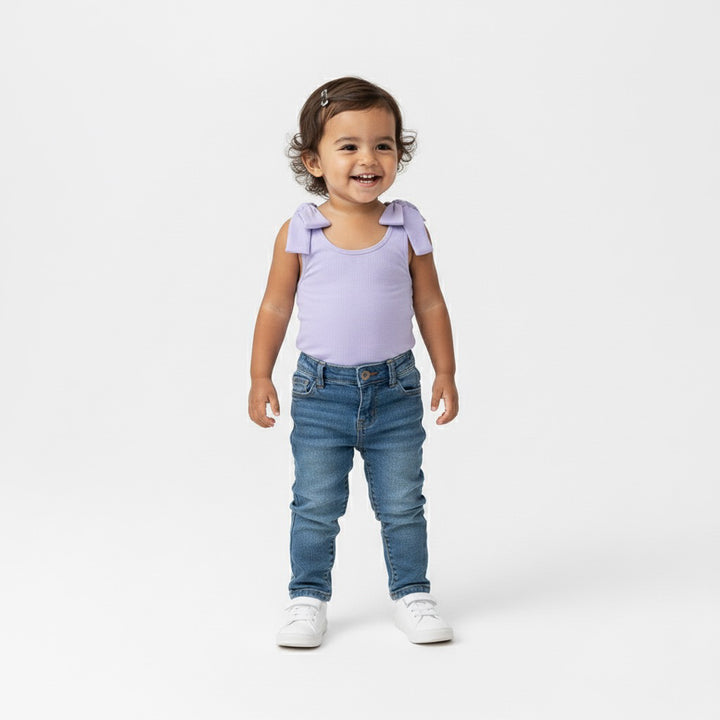 Toddler smiling in a Motch Lavender bow-shoulder bodysuit and blue jeans — a casual everyday look from the matching mommy-and-me collection, made for comfort and playful movement.