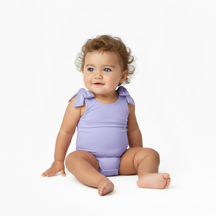Baby sitting and smiling in a Motch Lavender bow-shoulder bodysuit — soft, stretchy, and designed for matching mommy-and-me moments with everyday comfort and movement in mind.
