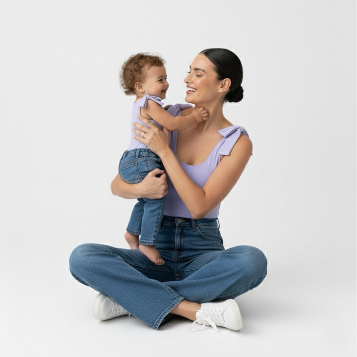 Mom and baby smiling together in matching Motch Lavender bow-shoulder bodysuits with jeans — a soft, stretchy mommy-and-me outfit designed for comfort, connection, and everyday matching moments.