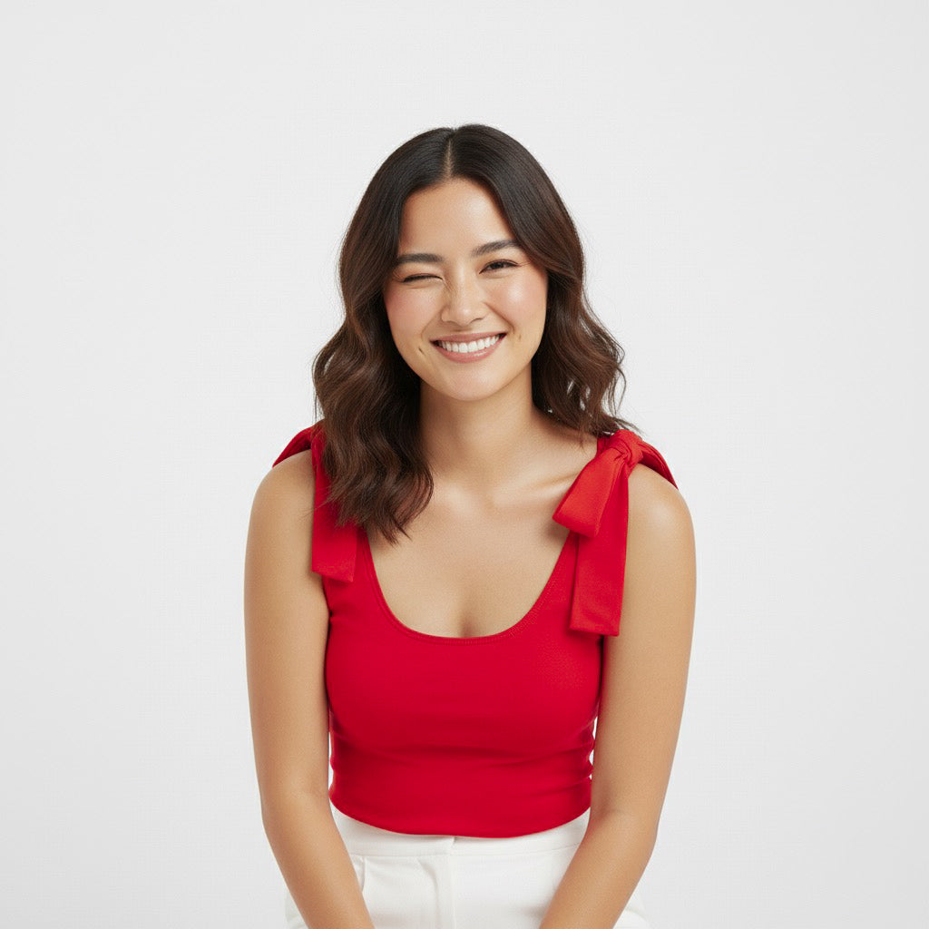 Woman smiling and winking while wearing a Red bow-shoulder bodysuit from Motch, part of a matching mommy-and-me outfit set, styled with white pants for a fun and festive look.