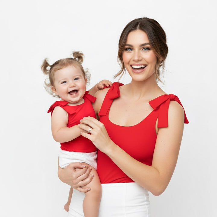 Mom and baby smiling in matching red Motch bow-shoulder bodysuits — a joyful mommy-and-me look designed for comfort, connection, and everyday moments.