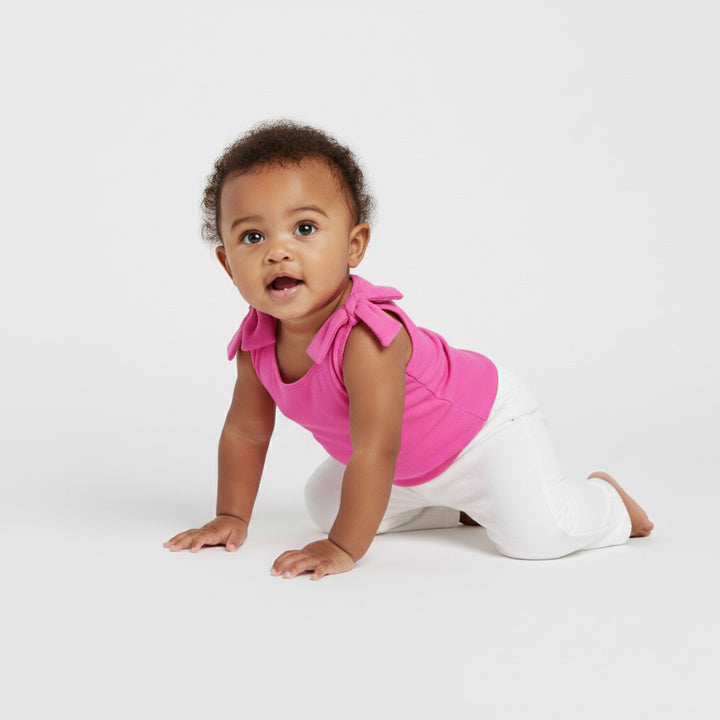 Baby crawling in a bright pink Motch bow-shoulder bodysuit and white pants — soft, stretchy, and made for everyday play and picture-perfect matching moments.