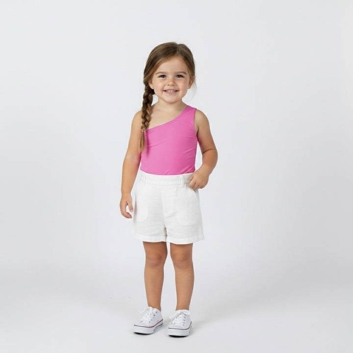 Smiling toddler girl in a hot pink Motch one-shoulder bodysuit and white shorts — a bright, playful mommy-and-me matching look.
