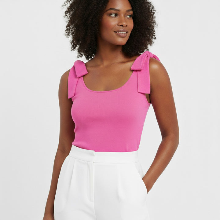 Woman wearing a bright pink bow-shoulder bodysuit from Motch, part of a matching mommy-and-me outfit set, styled with white pants against a clean white backdrop.