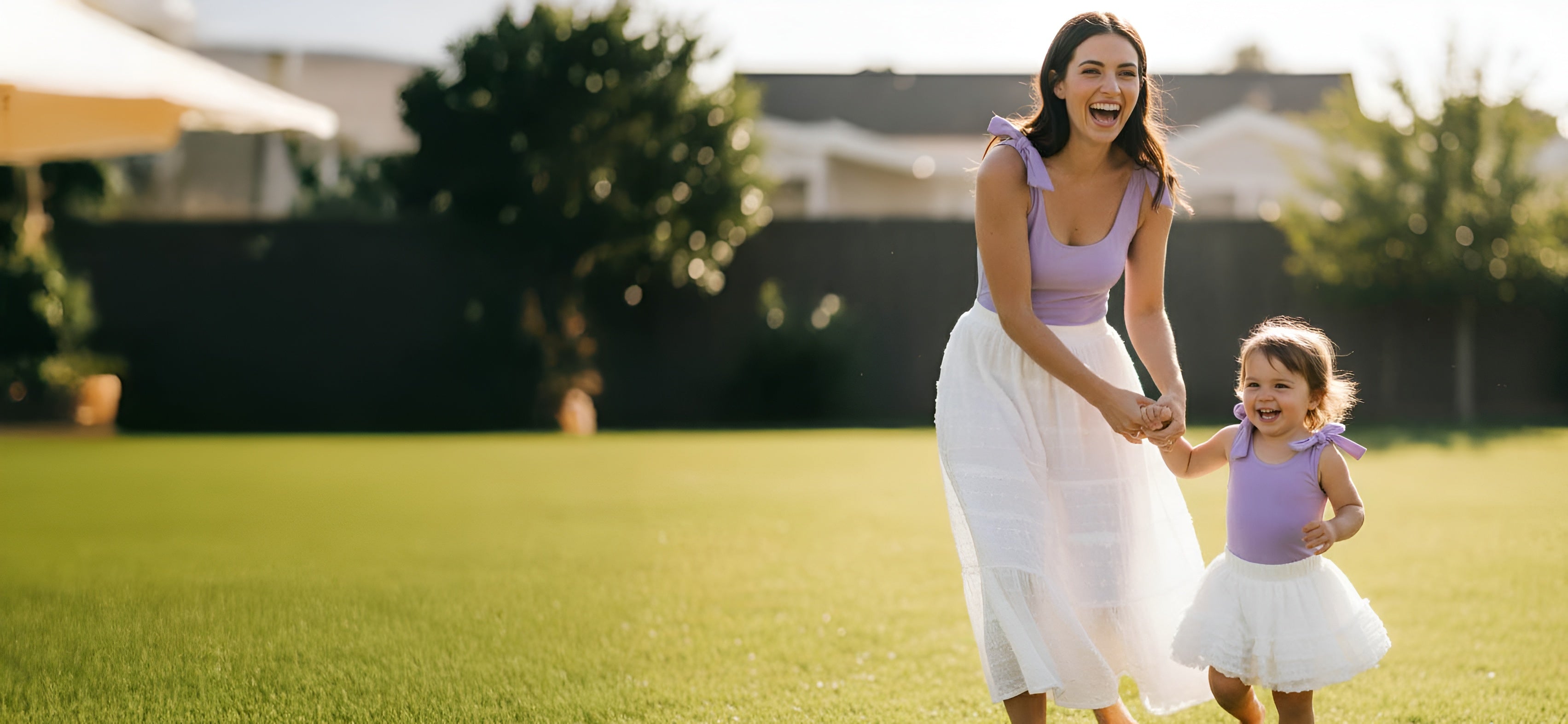 Mother and toddler holding hands outdoors wearing matching lavender one-shoulder bodysuits by Motch