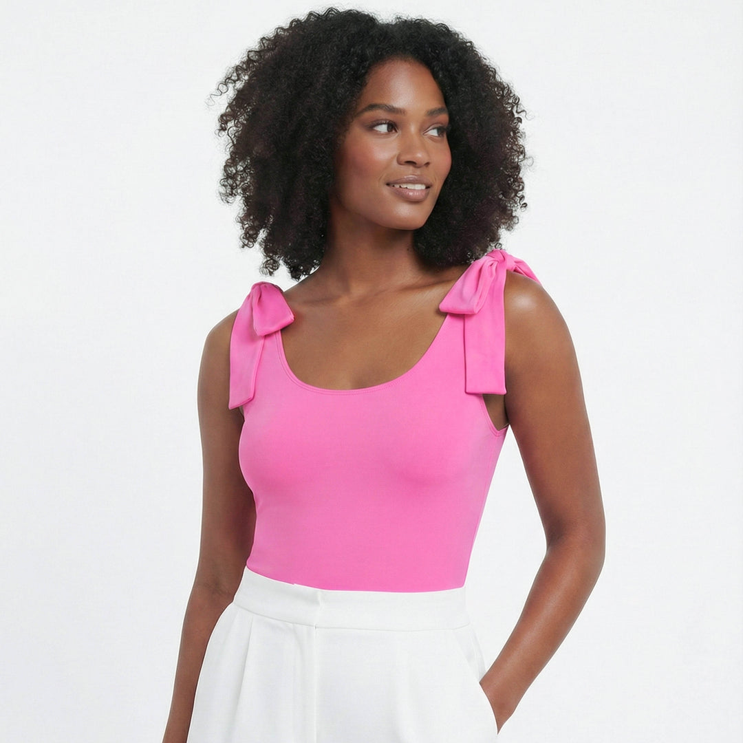 Woman wearing a pink top with bow straps on a white background