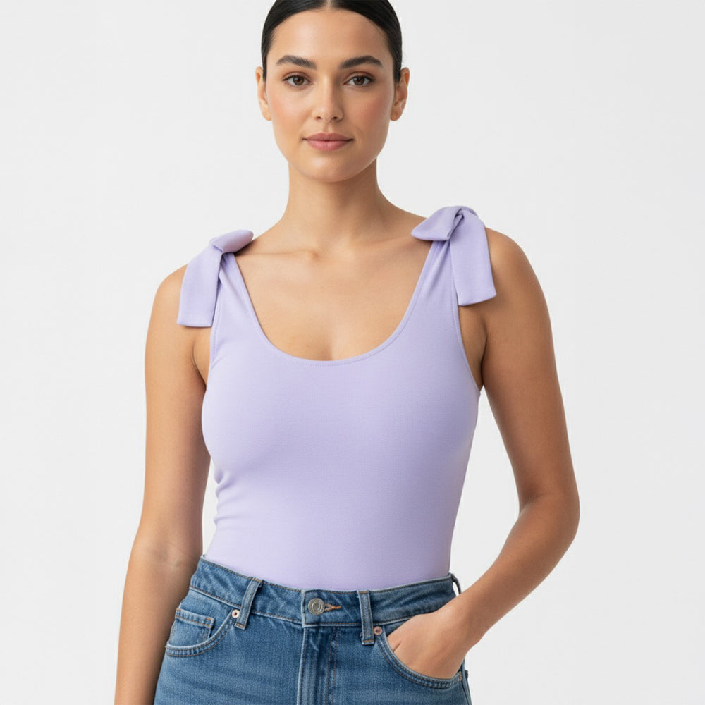 Woman wearing a Lavender bow-shoulder bodysuit from Motch, part of a matching mommy-and-me outfit set, styled with jeans in a bright studio — a soft, timeless take on everyday matching.